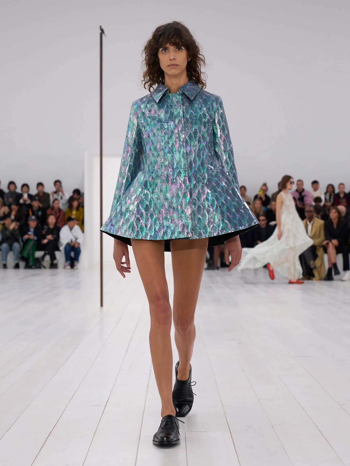 LOEWE Women's SS 25 Runway Collection- A model elegantly walks the runway, wearing a striking yellow coat that highlights the latest fashion trends.