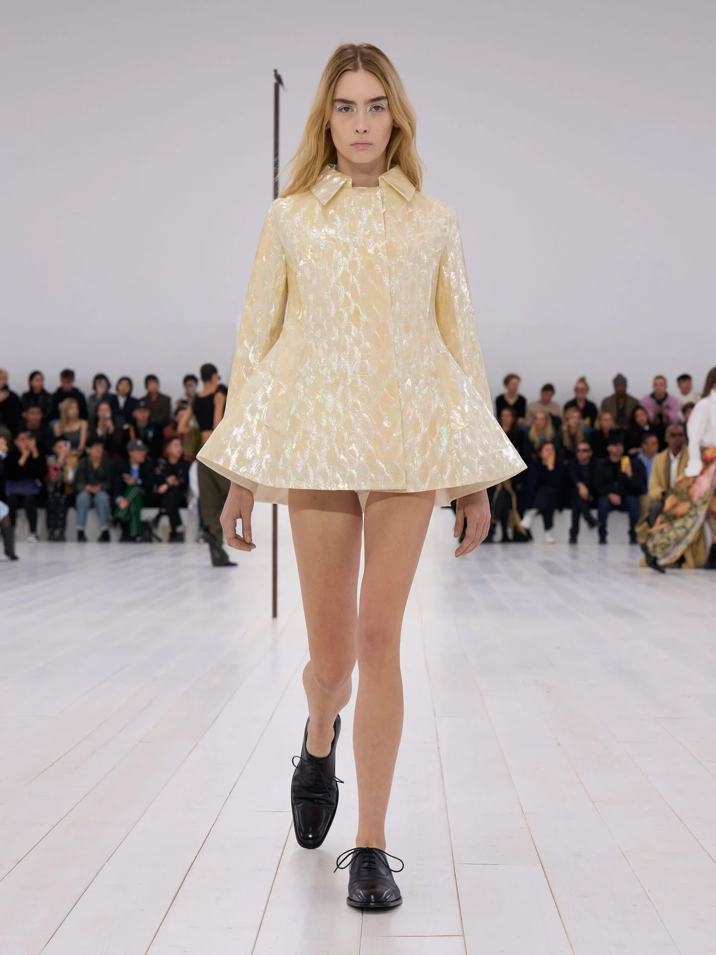 LOEWE Women's SS 25 Runway Collection - A model elegantly walks the runway, wearing a striking yellow coat that highlights the latest fashion trends.